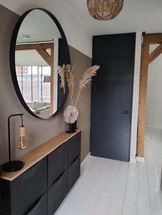 a large round mirror hanging on the side of a wall next to a black cabinet