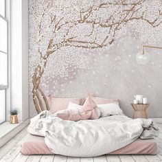 a white bed sitting under a tree covered in pink and white flowers next to a window