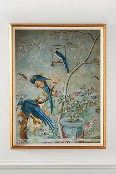 two blue birds sitting on top of a tree in front of a wall with flowers