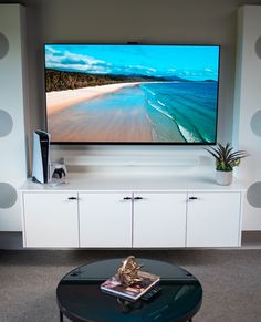 a flat screen tv sitting on top of a white entertainment center next to a black coffee table