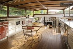 an open kitchen and dining area on a boat with wood floors, white walls and ceiling