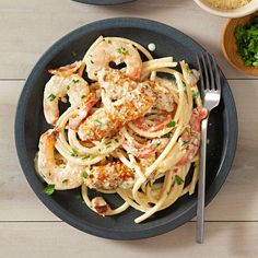 pasta with shrimp and parmesan cheese in a black bowl on a wooden table