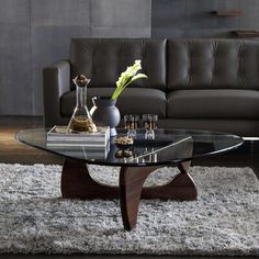 a living room with a couch, coffee table and vases on the rug in front of it