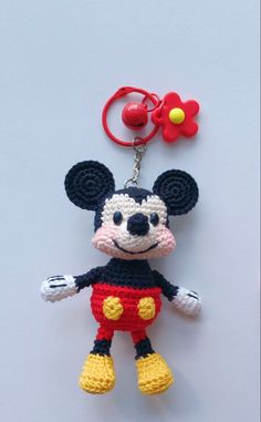 a crocheted mickey mouse keychain with a red and yellow flower on it