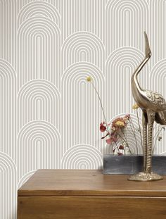 a wooden dresser topped with a vase filled with flowers next to a wallpapered wall