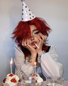 a woman with red hair wearing a party hat and holding her hand to her face