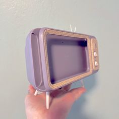 a hand holding a small purple tv on a toothpick holder with pins sticking out of it