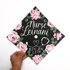 a hand holding up a graduation cap with flowers on it that says nurse lenani c