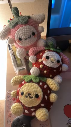 two stuffed animals sitting on top of each other near a computer keyboard and monitor screen