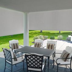 an outdoor dining area with patio furniture and shades