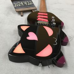 a black cat shaped guitar with pink eyes