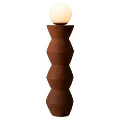 a brown vase with a white ball on top and a light in the middle next to it