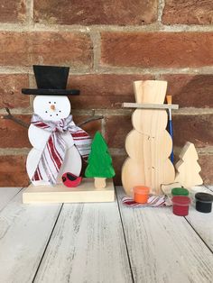 two snowmen made out of wood sitting next to each other on a wooden table