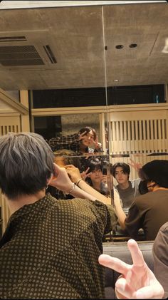 a group of people standing in front of a mirror with their hands up to the side