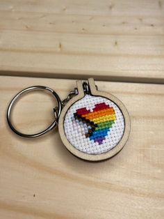 a cross stitch keychain with a rainbow heart on it