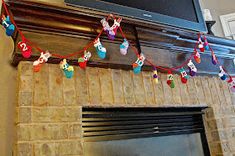 a television mounted above a fireplace with christmas lights on it's mantle and decorations