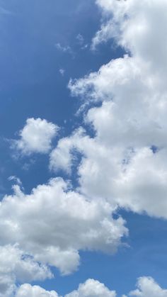 the airplane is flying high in the blue sky with white clouds above it and below