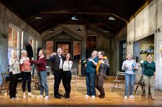 a group of people standing on top of a wooden floor in front of a building