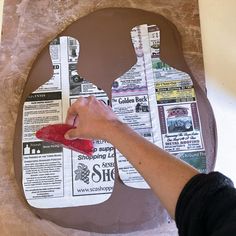 a person is painting the side of a paper cutout with newspaper clippings