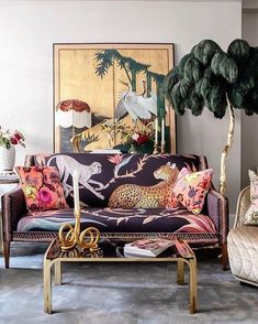 a living room filled with furniture and paintings on the wall next to a potted plant