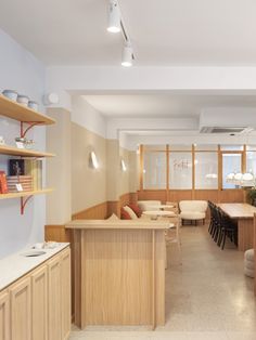 an empty room with tables and chairs in the center, along with shelving on the walls