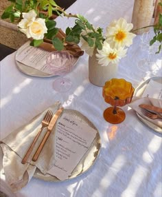 a table set with flowers and menus for an outdoor wedding reception in the sun