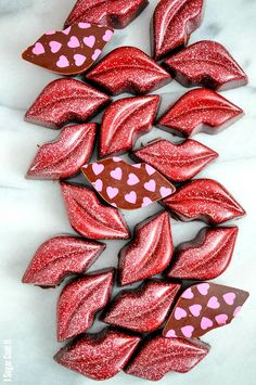 red and pink heart shaped chocolates are arranged on a white surface with hearts painted on them