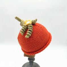 an orange knitted hat on top of a wooden mannequin