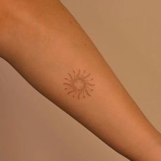 a woman's arm with a small sun tattoo on the left side of her arm