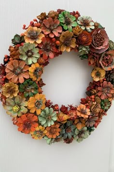 a wreath made out of fake succulents on a white door with an orange ribbon