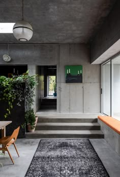 a room with concrete walls and stairs leading up to the second floor, along with an area rug on the floor