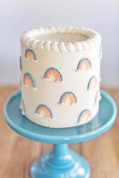 a white cake with rainbows on it sitting on a blue plate