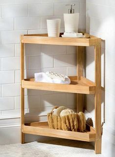 a wooden shelf with three shelves holding towels and other items on it in a white tiled bathroom