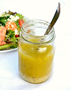 a salad in a jar next to a plate with a salad on it and a spoon