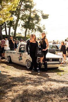 two women standing next to an old car