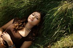 a young woman laying in the grass with her hands on her chest and eyes closed