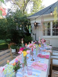 a table set up outside with flowers and candles on it for an outdoor dinner party