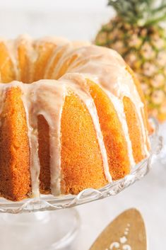 a pineapple bunt cake with icing sitting on a glass platter next to a pineapple