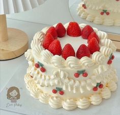 a cake with white frosting and strawberries on top is sitting on a table