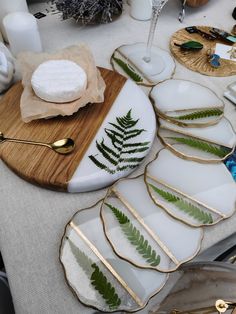 a table topped with plates covered in green leaves and gold rimmed utensils