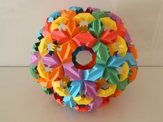 an origami ball made out of multicolored paper on a white surface