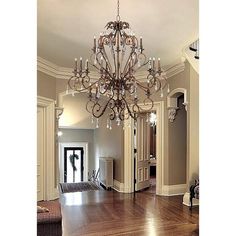 a chandelier hanging from the ceiling in a room with hardwood floors and walls