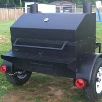 a large black bbq grill sitting on top of a grass covered field