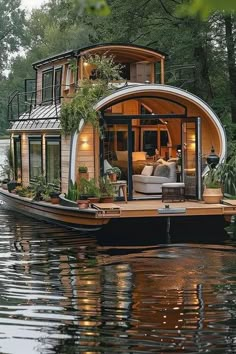 a houseboat floating on top of a lake surrounded by trees and greenery in the evening