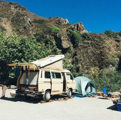 an old van is parked in front of a mountain with a camper and tent