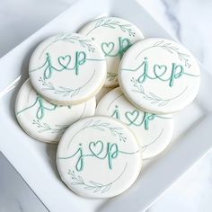 four decorated cookies on a white plate with green lettering and leaves around the edges that spell i love you