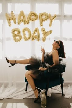 a woman sitting on a chair with the words happy body spelled out in gold letters