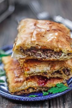 two meat and cheese pastries stacked on top of each other in a blue plate