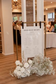 a sign that is sitting on top of a table with flowers in front of it