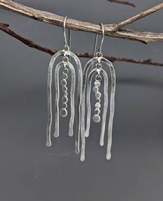 Light catching earrings with plenty of movement, both literally and esthetically. These sterling silver earrings are made with wire and discs, shaped and hammered by hand, soldered with jump rings for lots of constant movement. Lightweight and easy to wear. Delicately brushed finish.  Earrings measure 2 1/4" long from top of ear wire by 5/8" wide.   Surgical steel ear wires protect your pierced holes from irritation. Ear Rings Silver Earrings, Hammered Metal Jewelry, Kinetic Earrings, Chrysoprase Necklace, Hammered Jewelry, 18k Gold Necklace, Silver Jewelry Design, Hammered Metal, Wire Pendant